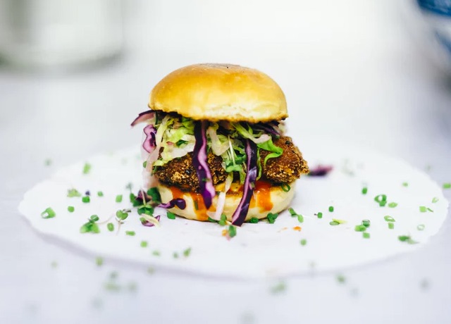 A chicken burger topped with lettuce and cabbage.